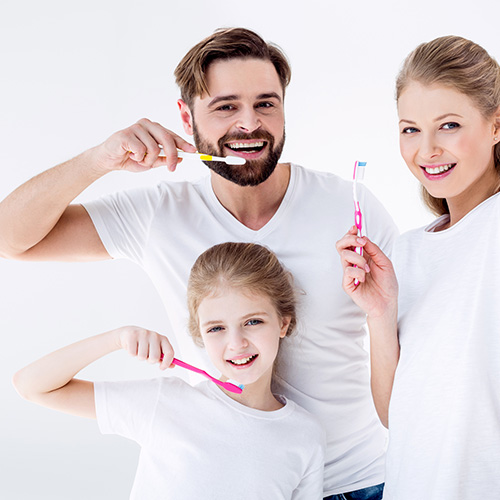 A child, mom, and dad brushing their teeth