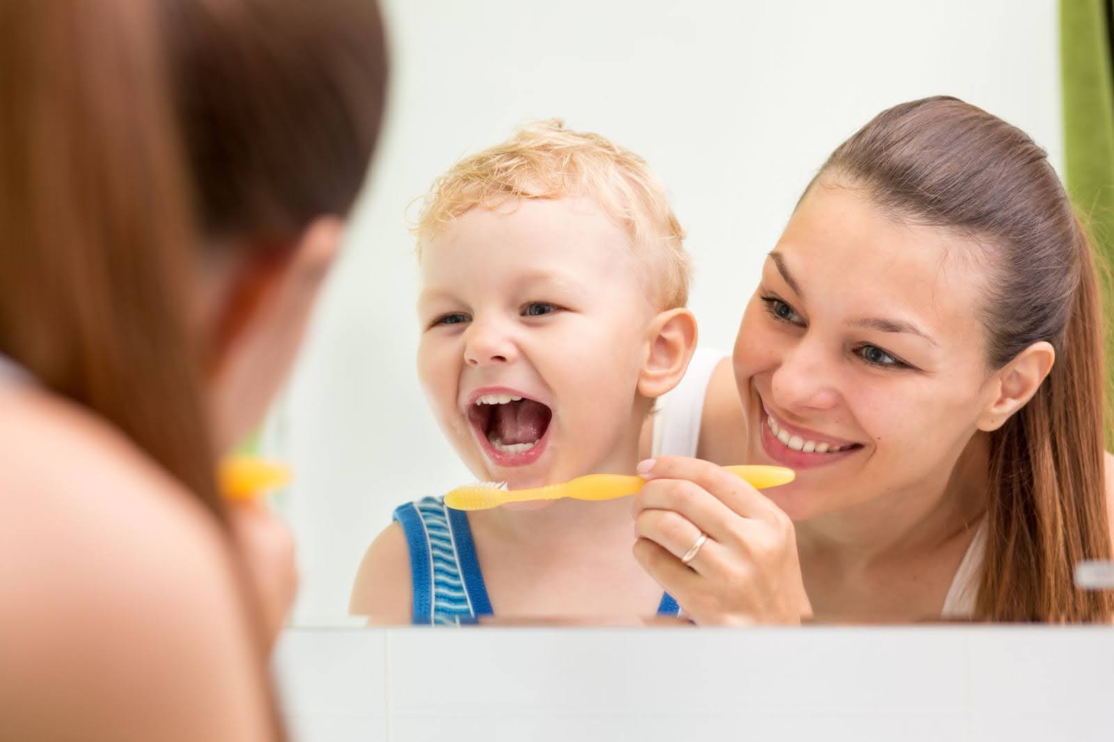A parent brushing their child’s teeth to prevent a child's dental emergency