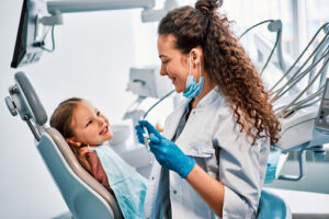 A dentist teaching a child about how often kids should go to the dentist.