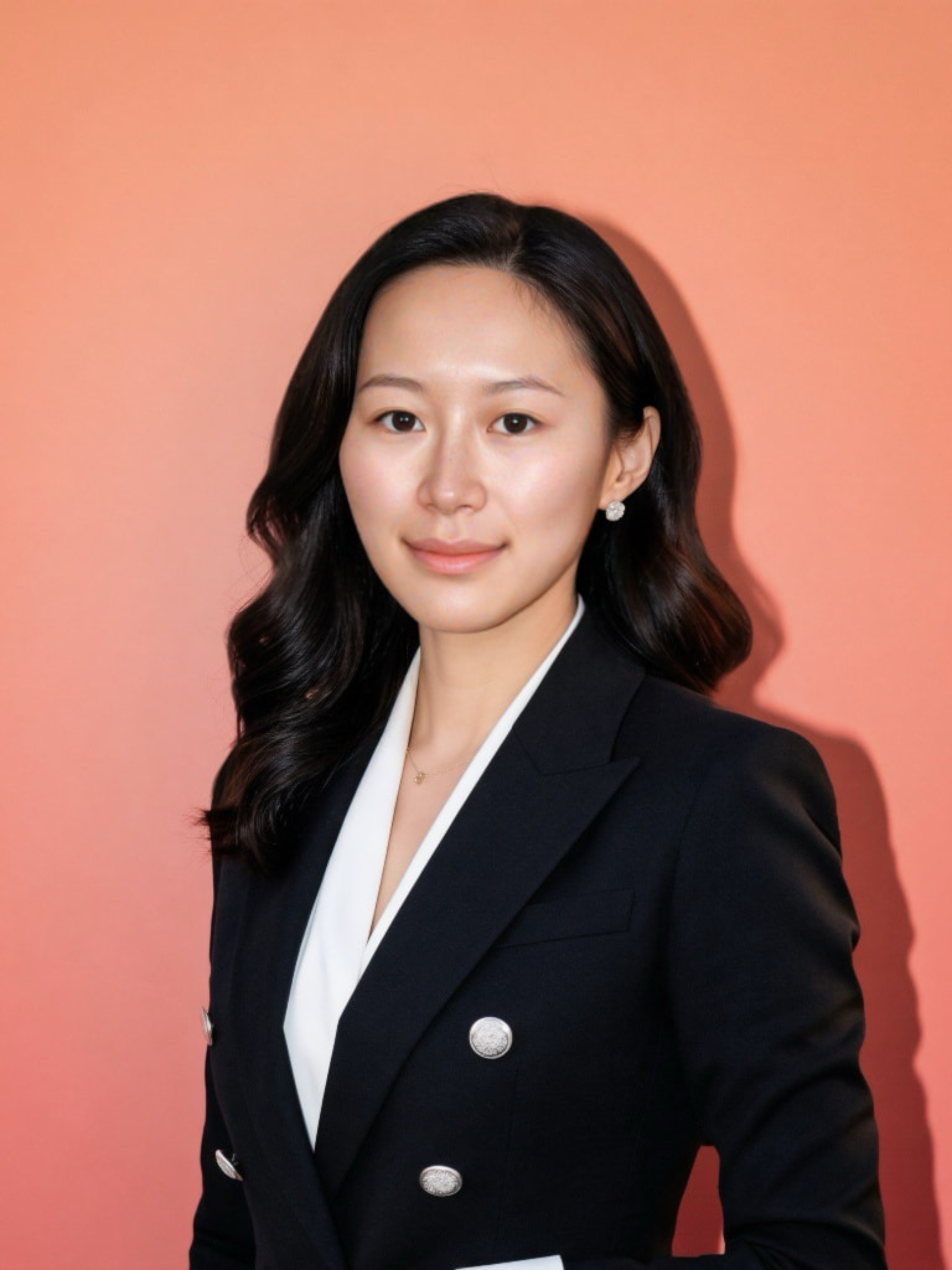New Project - 2026-09-30T173006222 - Dino Kids Dental - Dino Kids Dental Portrait of an Asian woman in a black blazer with silver buttons, white blouse, against a peach background with soft lighting.